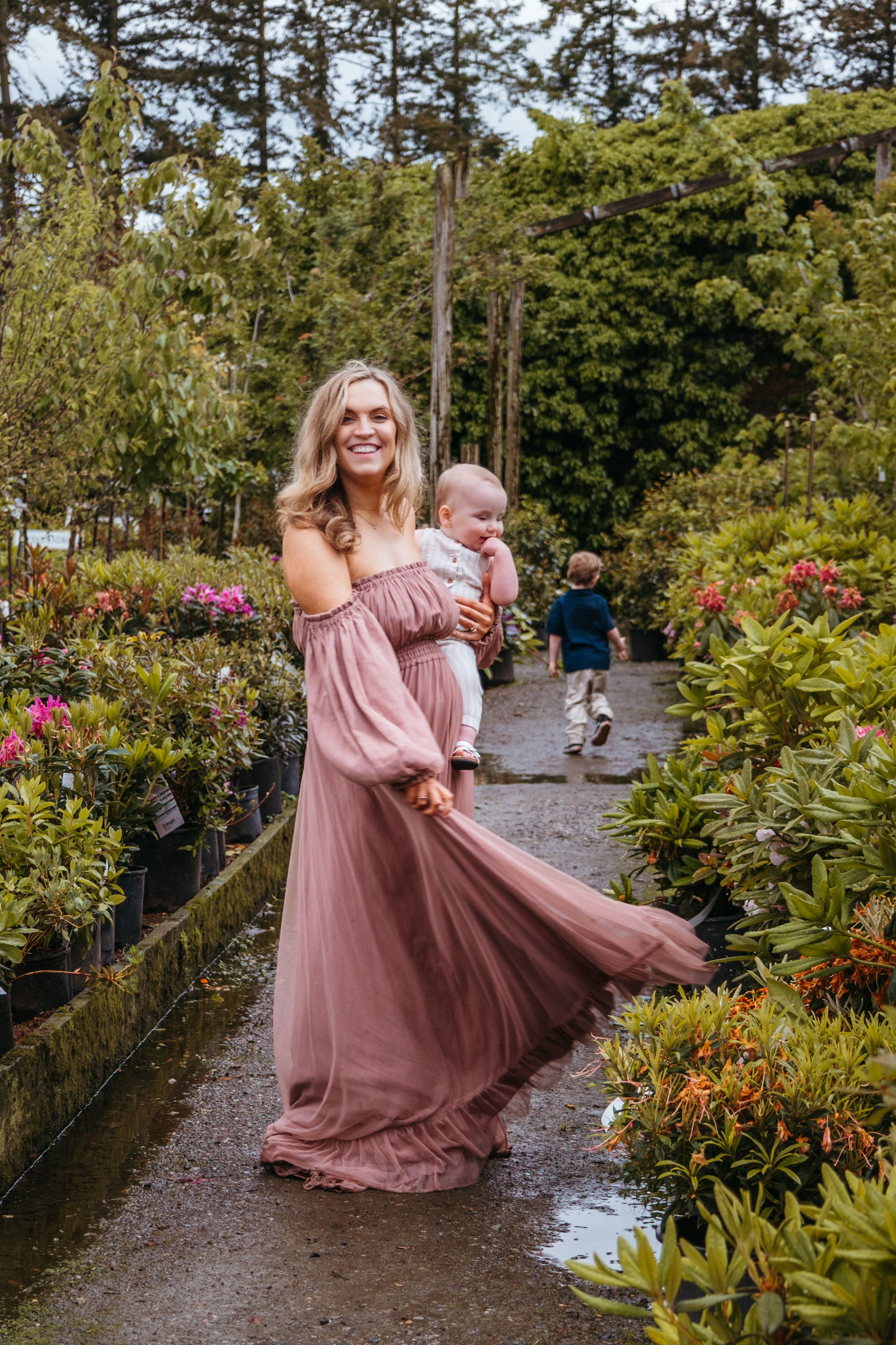 A couple dances joyfully along a garden path surrounded by lush greenery and colorful flowers.