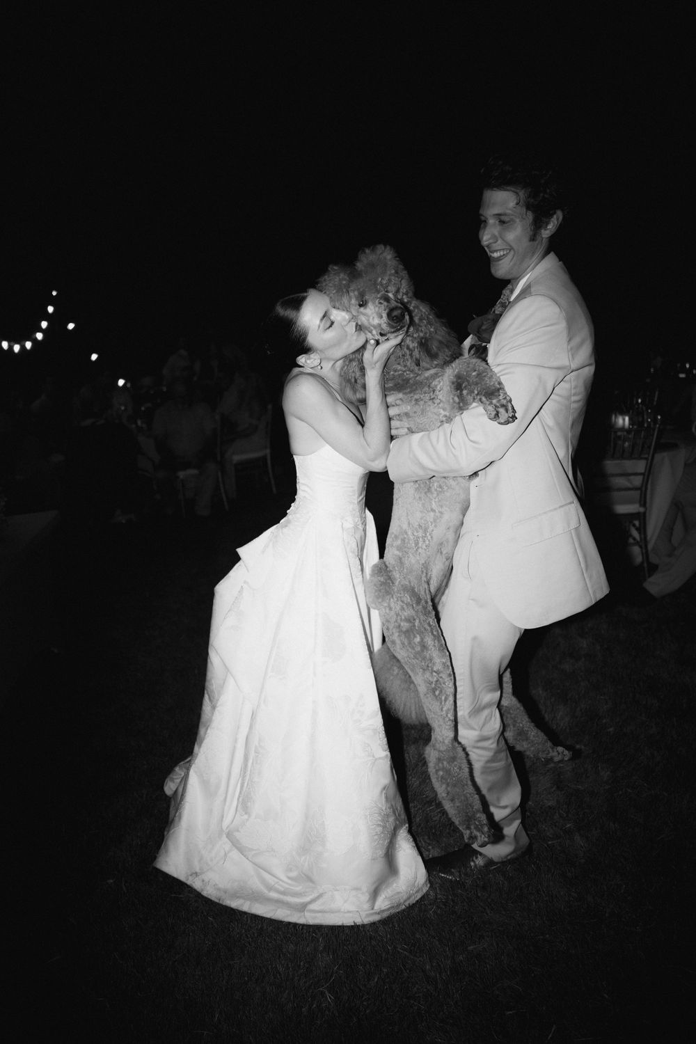 Black and white nighttime dance sequence at an outdoor wedding reception.
