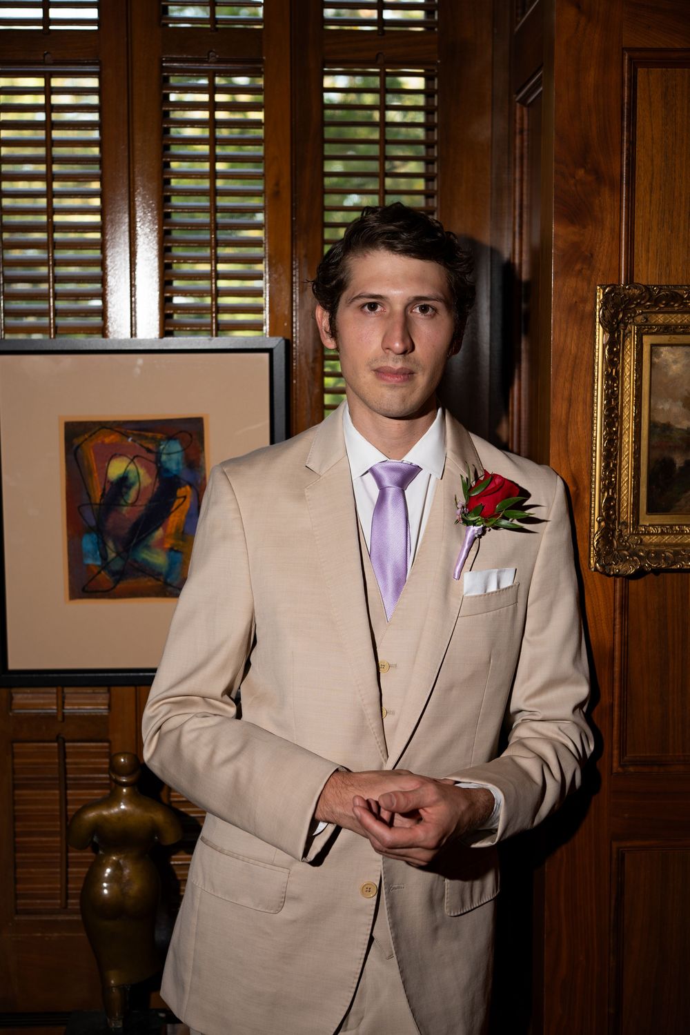 A series of photos showing someone in a light beige suit with purple tie against wooden paneled walls.