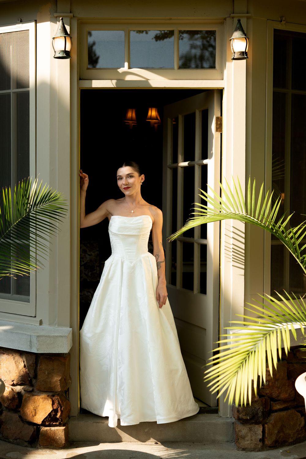 Wedding dress photos on porch with palm plants and white columns creating elegant outdoor setting.