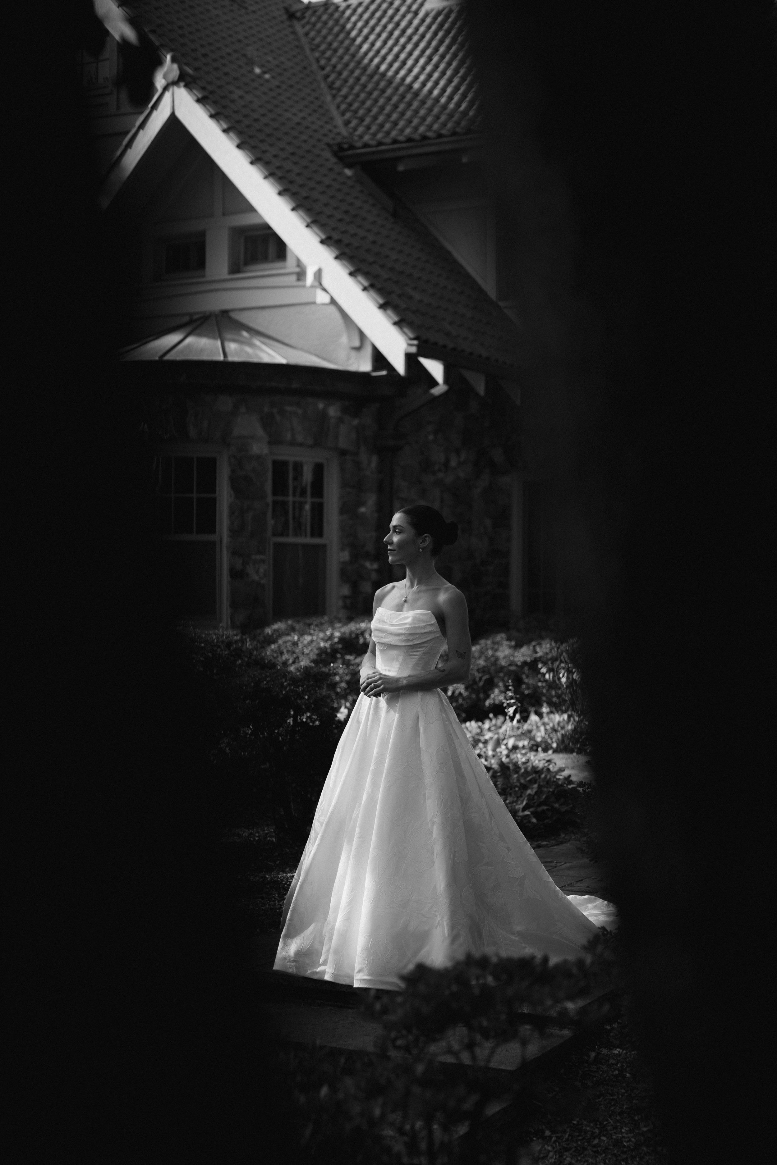 Dramatic black and white bridal portraits showing full wedding gown against architectural backdrop.