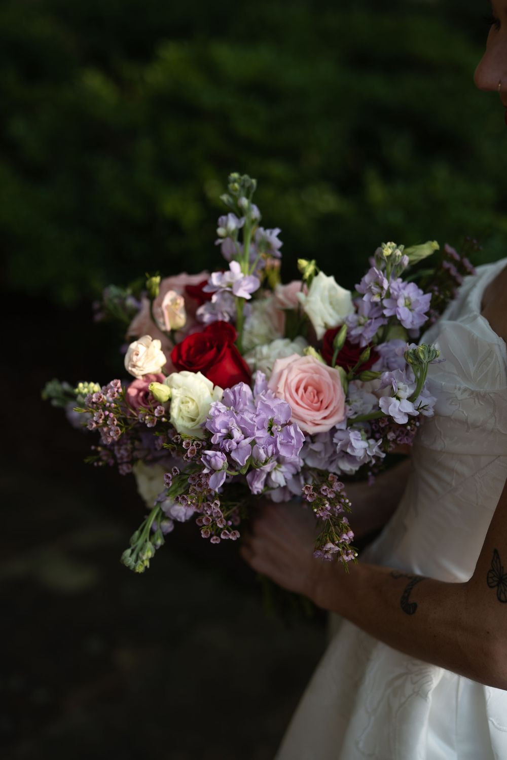 Close-up of romantic floral bouquet with pink roses, purple flowers, and delicate arrangements.