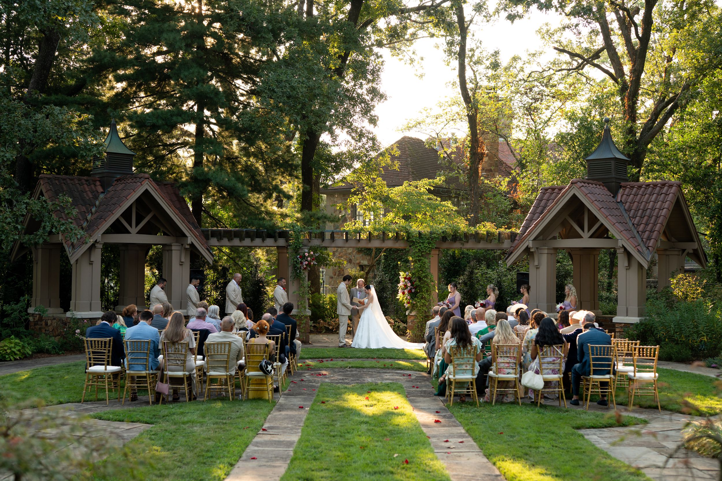 Outdoor wedding ceremony setup with wooden chairs and natural decor in a garden setting.