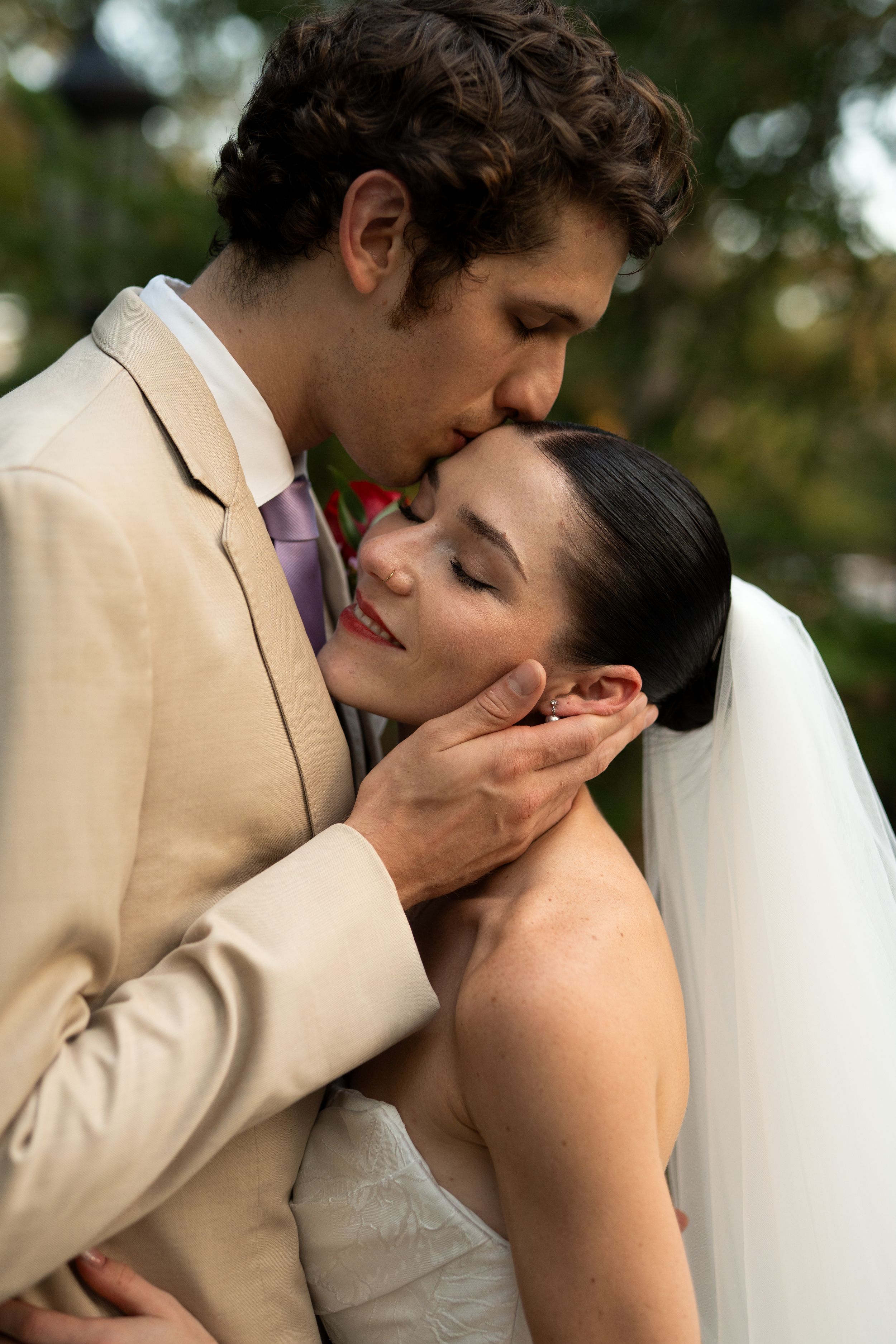 Romantic wedding kiss sequence between newlyweds in a tan suit and white dress.
