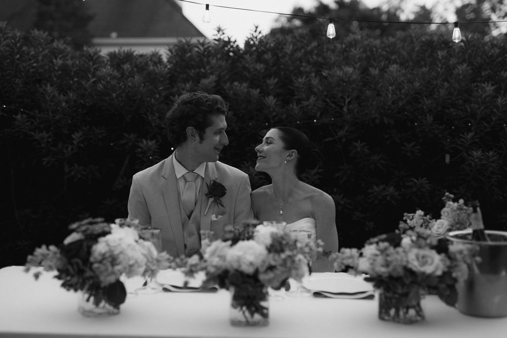 Wedding table settings silhouetted against a dark background with floral centerpieces.