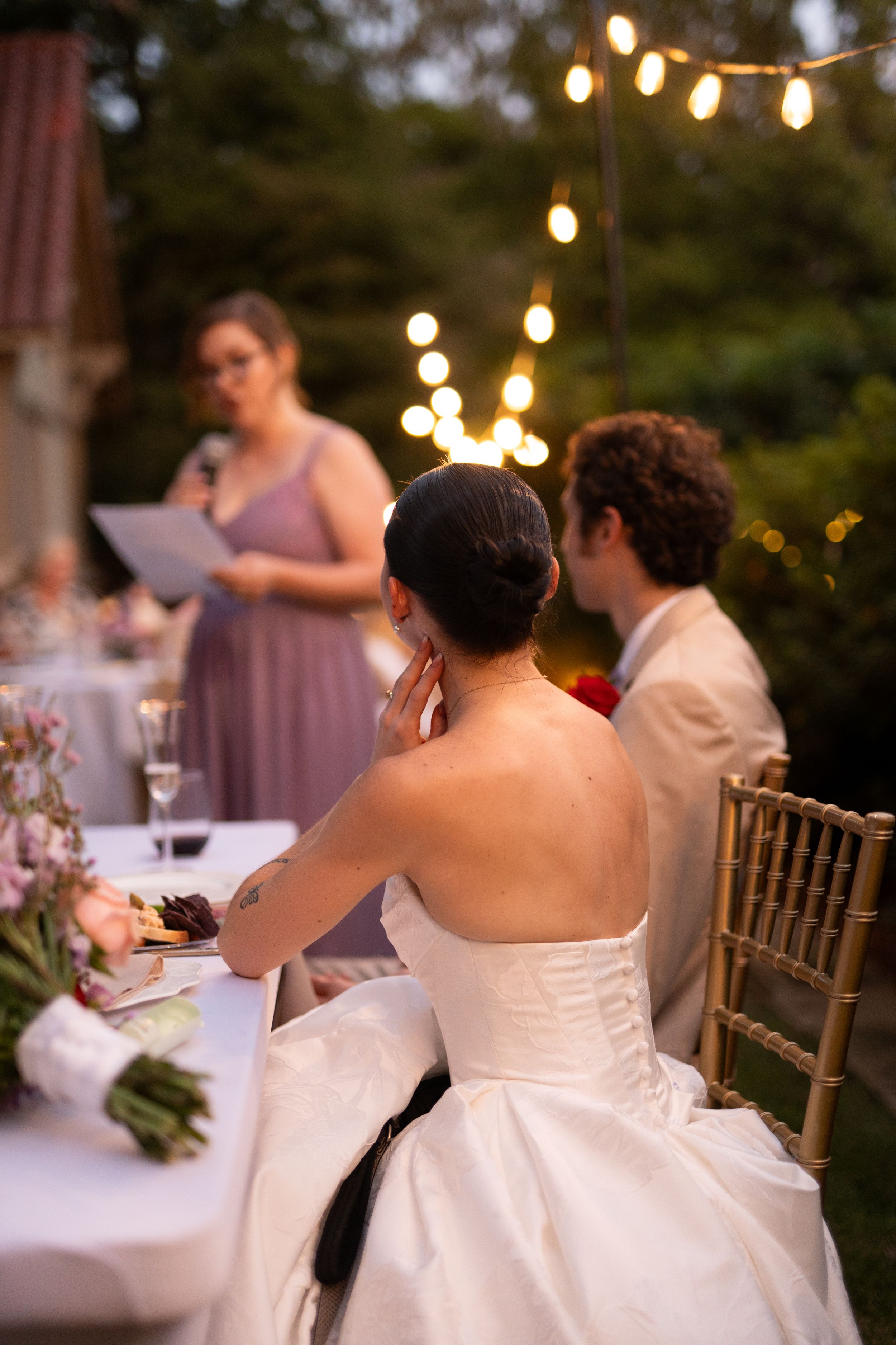 Evening wedding reception with string lights and guests seated at decorated tables.