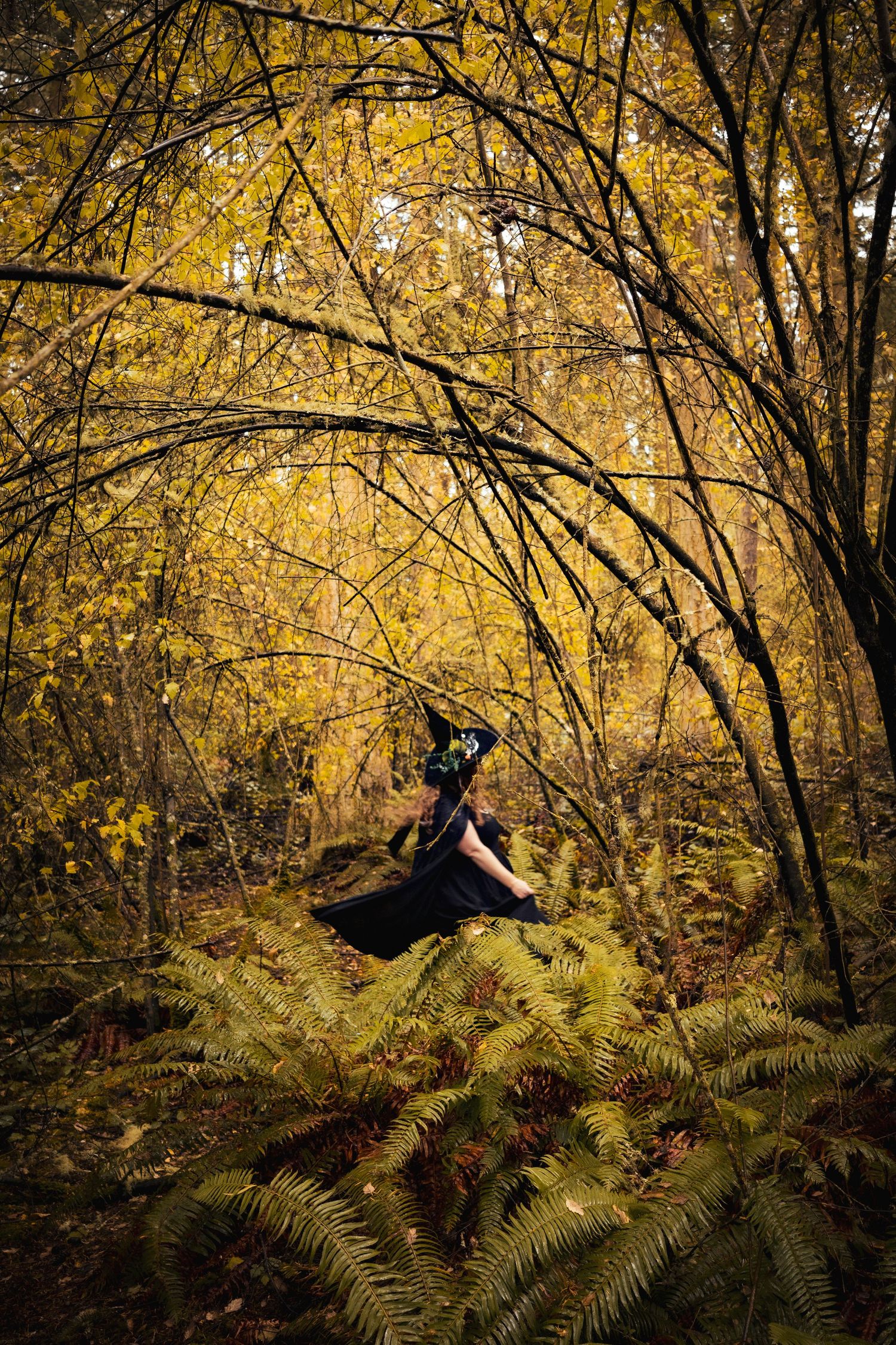 Woman wearing witch costume spinning in the forest.