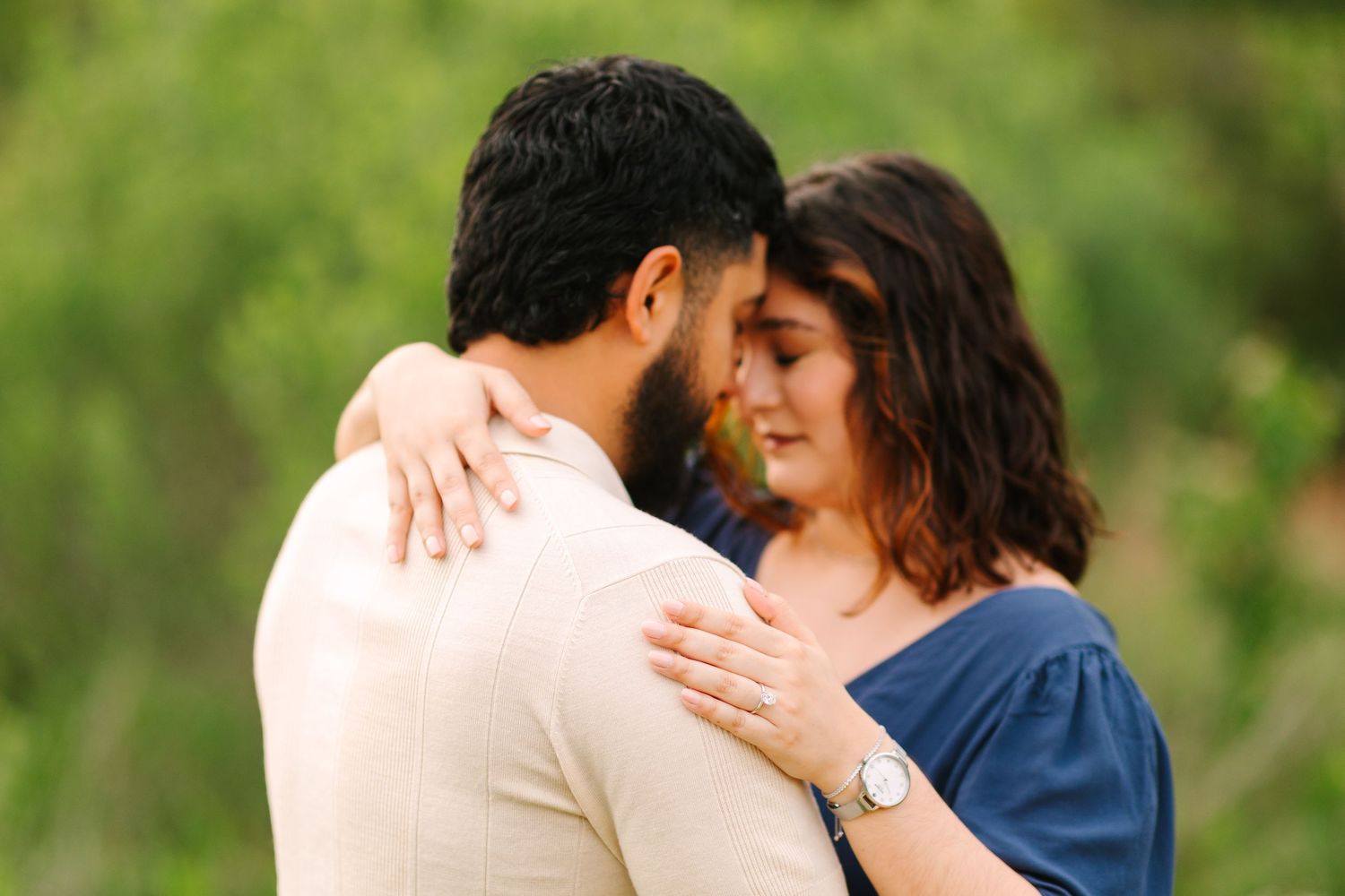Romantic couple sharing intimate moments in a sunlit outdoor garden setting.