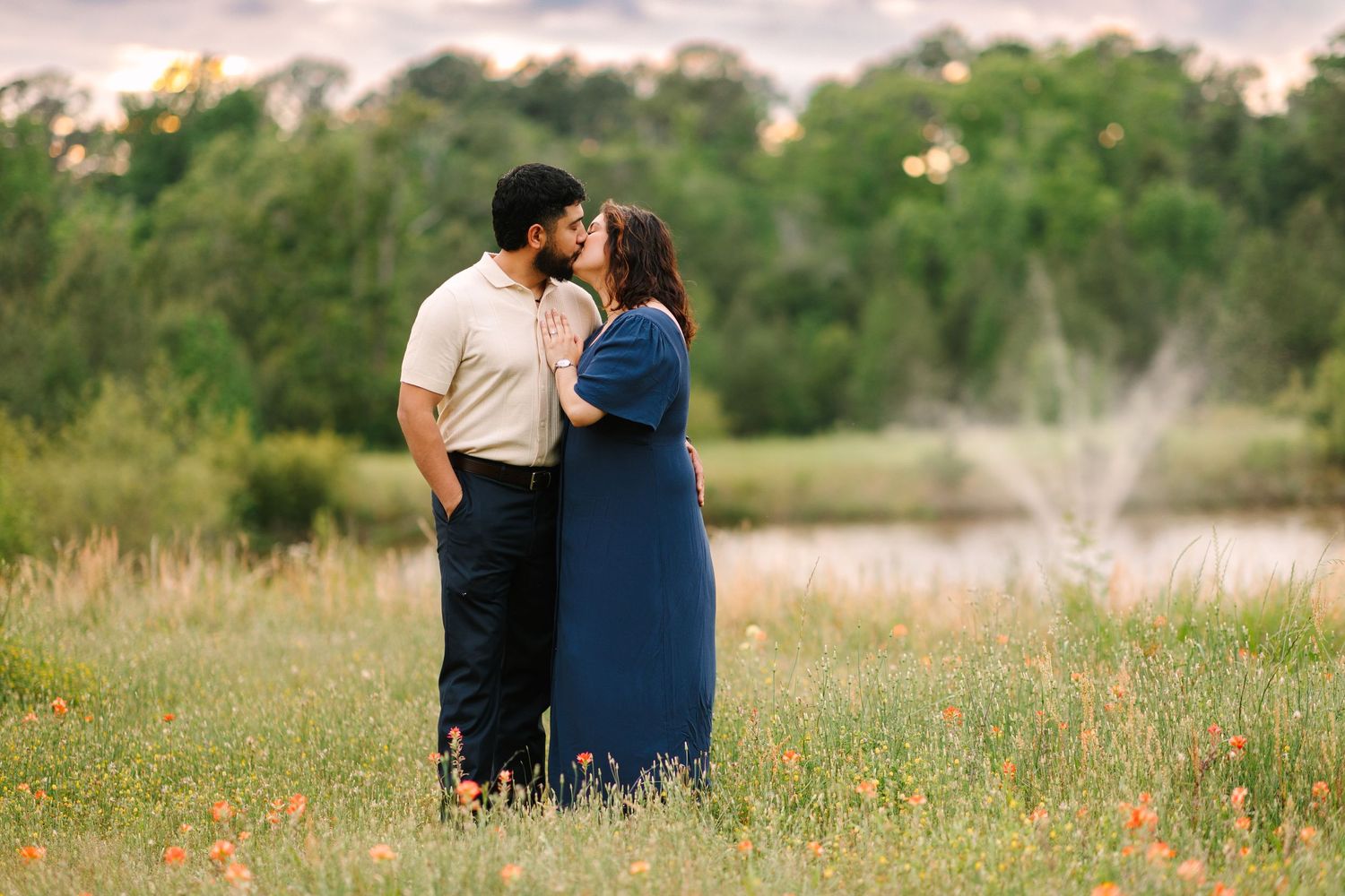 Couple shares an intimate moment in a wildflower field during golden hour.