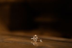 Sparkling diamond engagement ring on dark wooden surface.