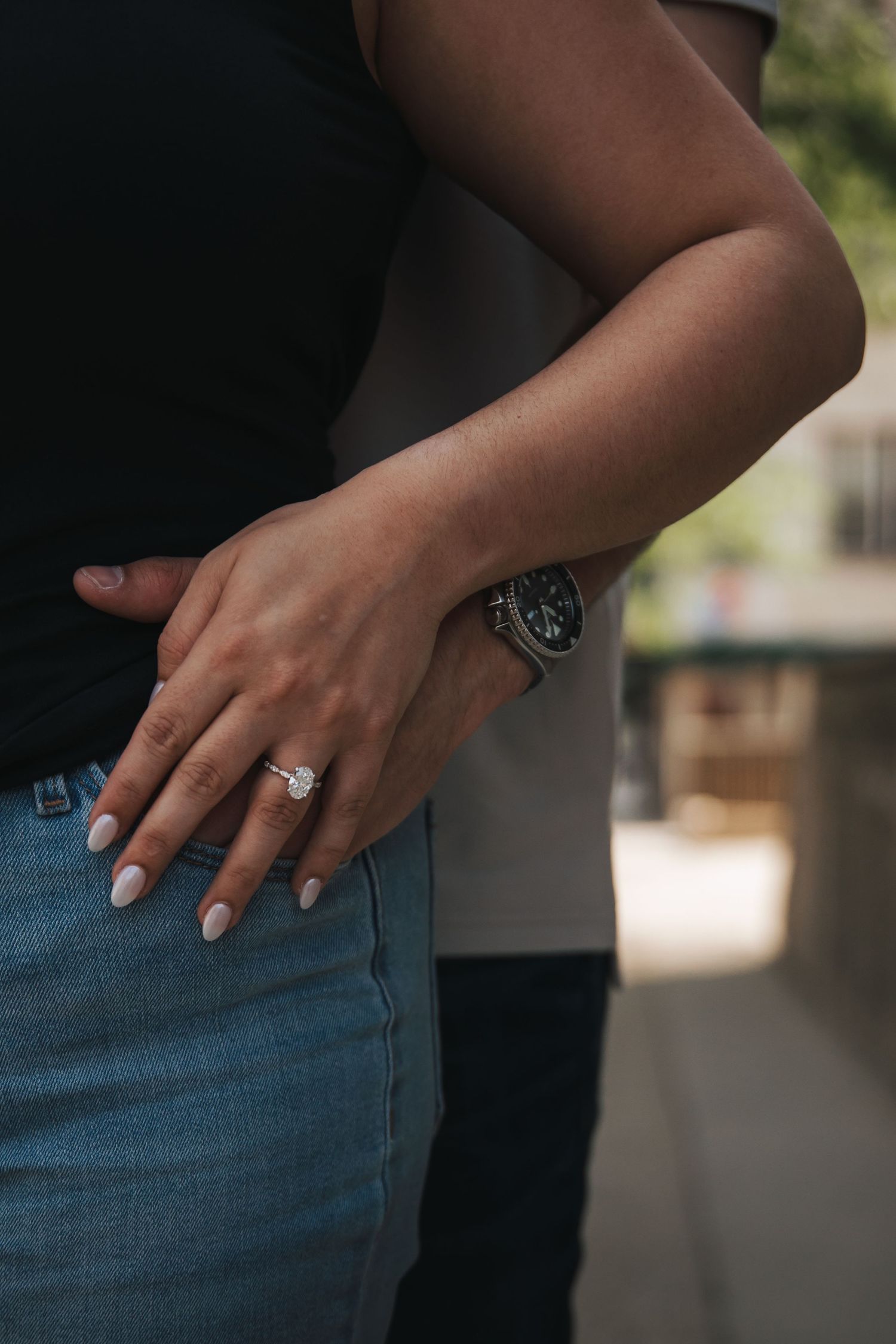 Close-up of engagement ring on hand against denim background.