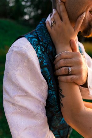 Close-up shot of a couple embracing showing details of formal attire and jewelry.