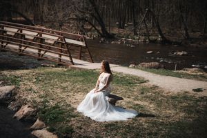 White dress flowing across rustic wooden bridge in natural setting.
