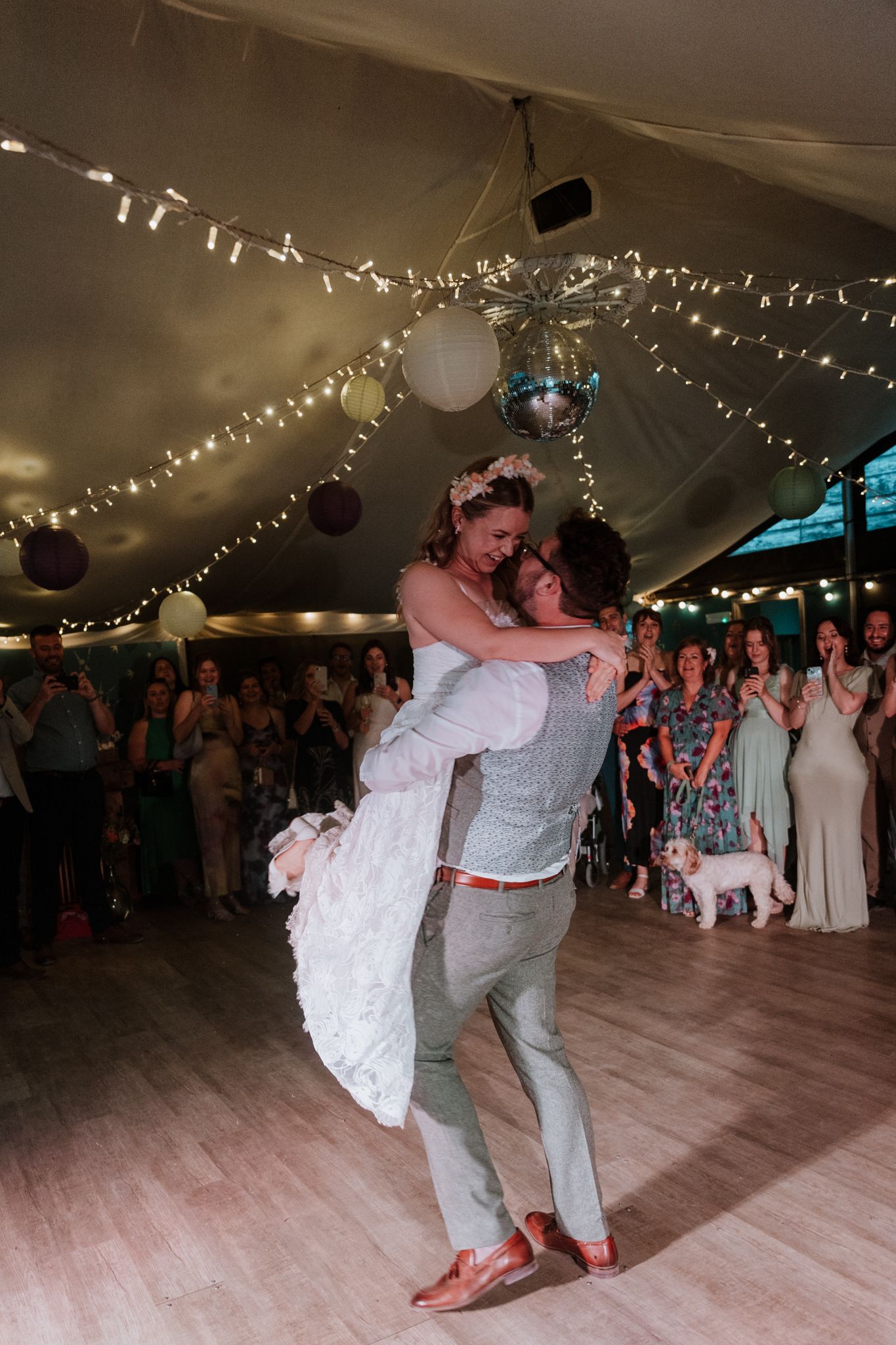 Wedding couple performs an energetic dip during their first dance under twinkling lights at their reception at Wilde Lodge
