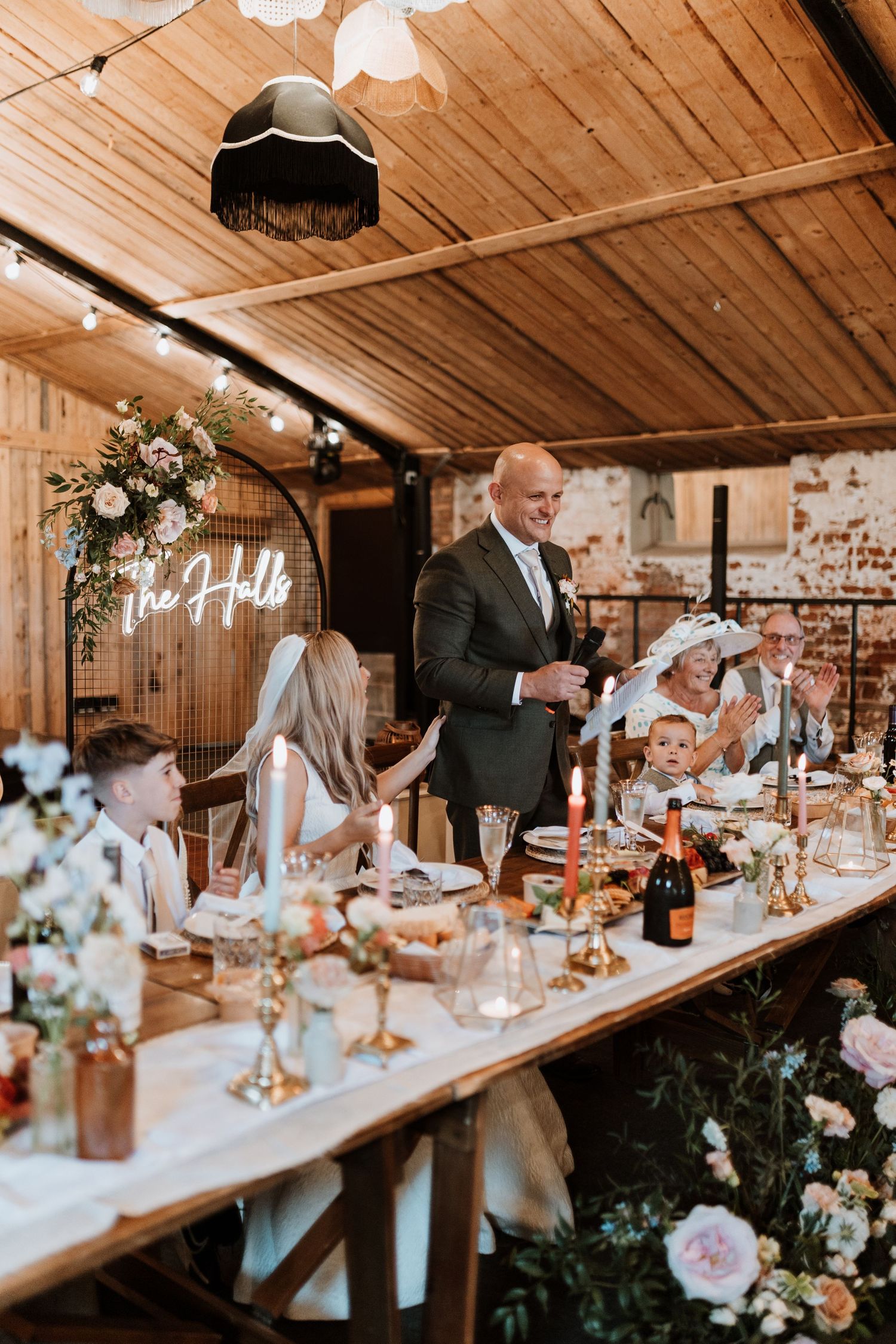 Elegant rustic wedding reception setup with wooden table, floral arrangements and candlesticks under wooden beamed ceiling at Stanford Farm
