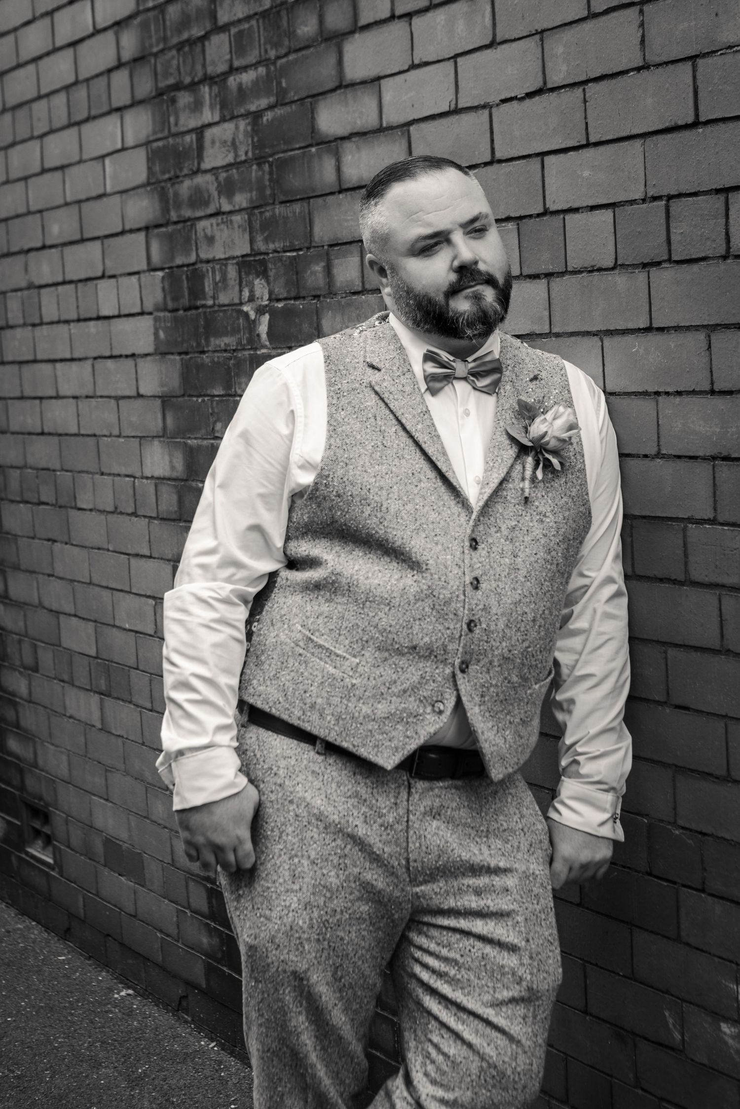 Black and white photo series shows person in vintage-inspired outfit with tweed vest and bowtie against brick wall.
