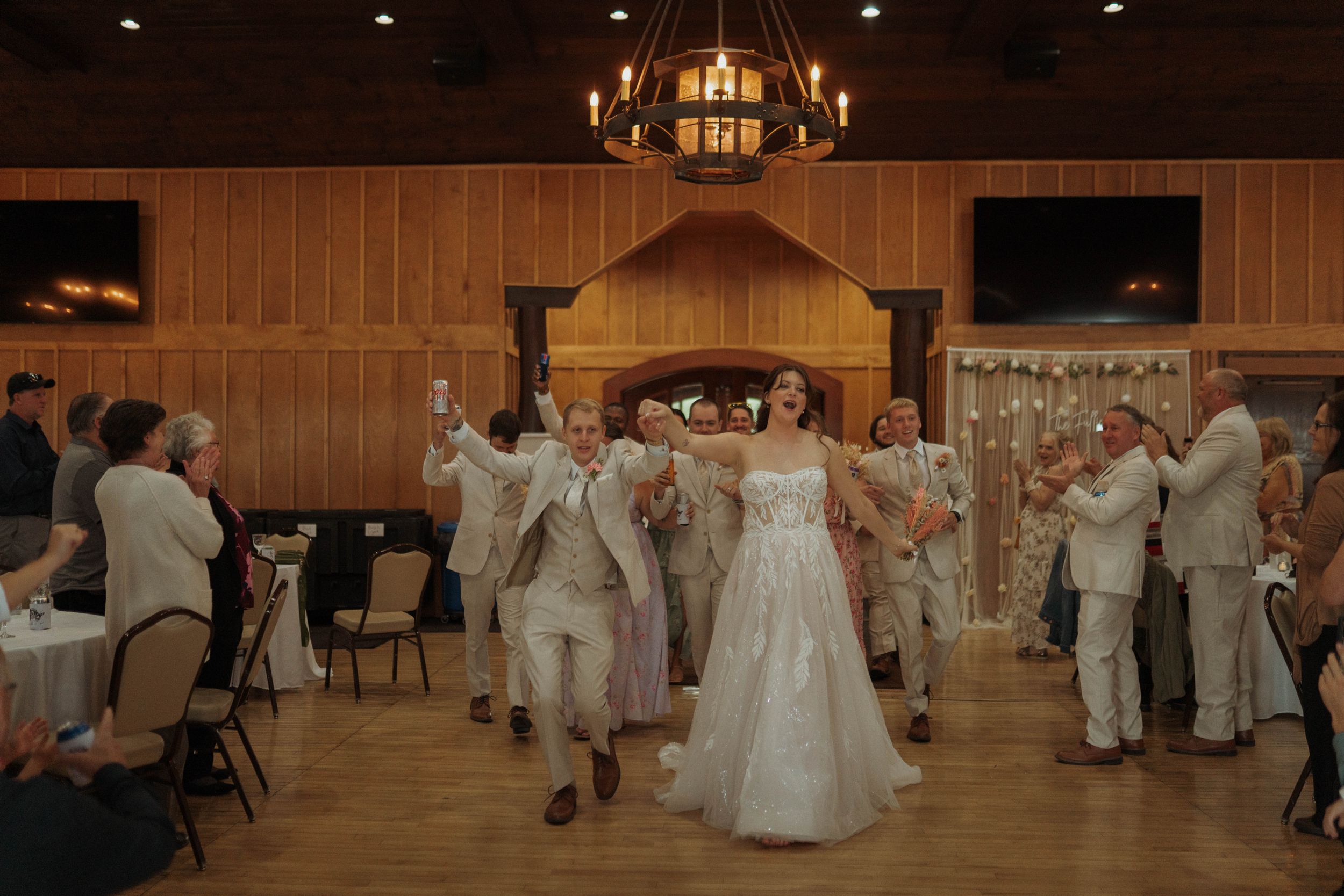 Wedding celebration in a rustic venue with guests dancing under warm lighting.