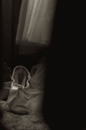 Elegant white shoes photographed in dramatic low-key lighting against dark background.