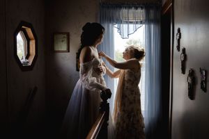 Silhouetted figures prepare in a dimly lit room with window light.