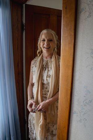 Joyful moments captured near a window with soft lighting and elegant attire.