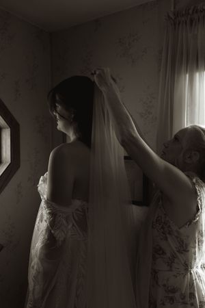 Artistic silhouettes of wedding preparations against a window with soft natural light streaming in.