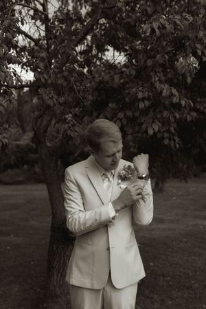 Emotional black and white portrait in a garden setting wearing a white suit.