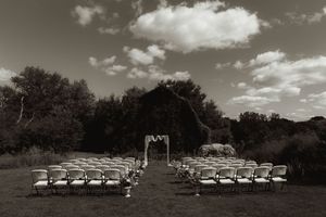 Panoramic view of white wedding chairs set up outdoors under a cloudy sky.