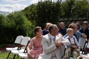Wedding guests gather on a grassy hillside during an outdoor ceremony.