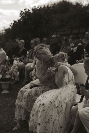 Wedding attendees seated in rows of white chairs during an outdoor ceremony.
