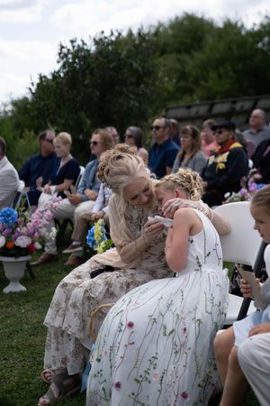 Wedding guests in floral dresses seated during an outdoor ceremony.