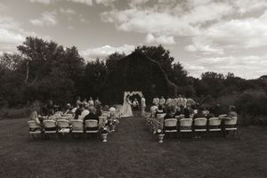 Panoramic view of an outdoor wedding ceremony with white chairs arranged on a grassy hillside.