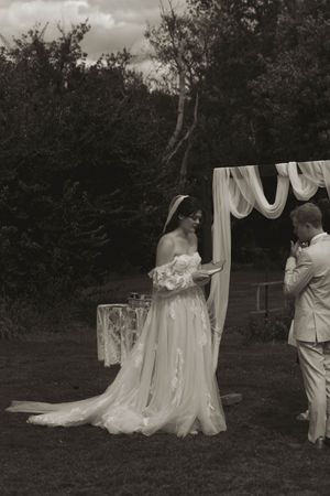 Black and white photo of an outdoor wedding ceremony with flowing white fabric decorations.