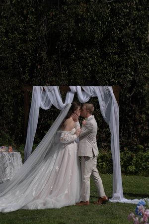Elegant outdoor wedding ceremony setup with white draping and floral arrangements.