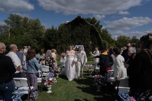 Wedding guests gather outdoors for a celebration under partly cloudy skies.