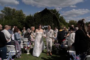 Wedding guests gather outdoors for celebration under cloudy skies.