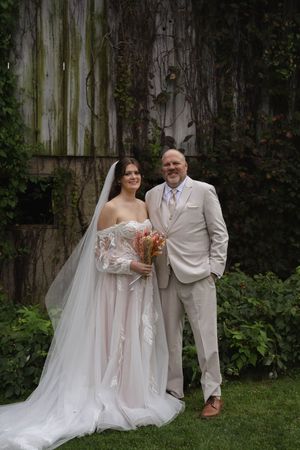 Elegant wedding portraits against weathered wood fence showing flowing white gown and light colored suit.