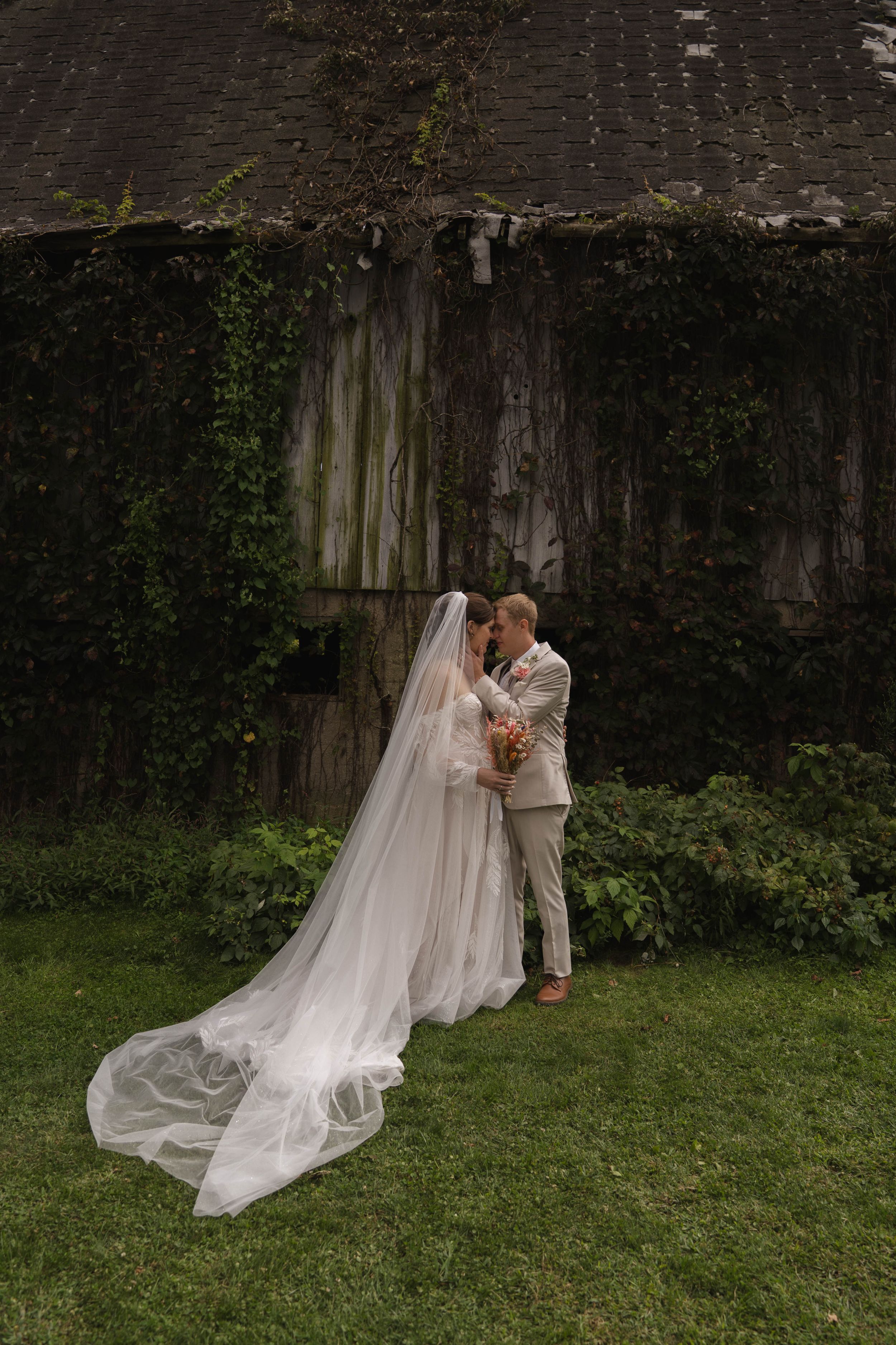 Elegant wedding scene with flowing veil against natural outdoor backdrop.