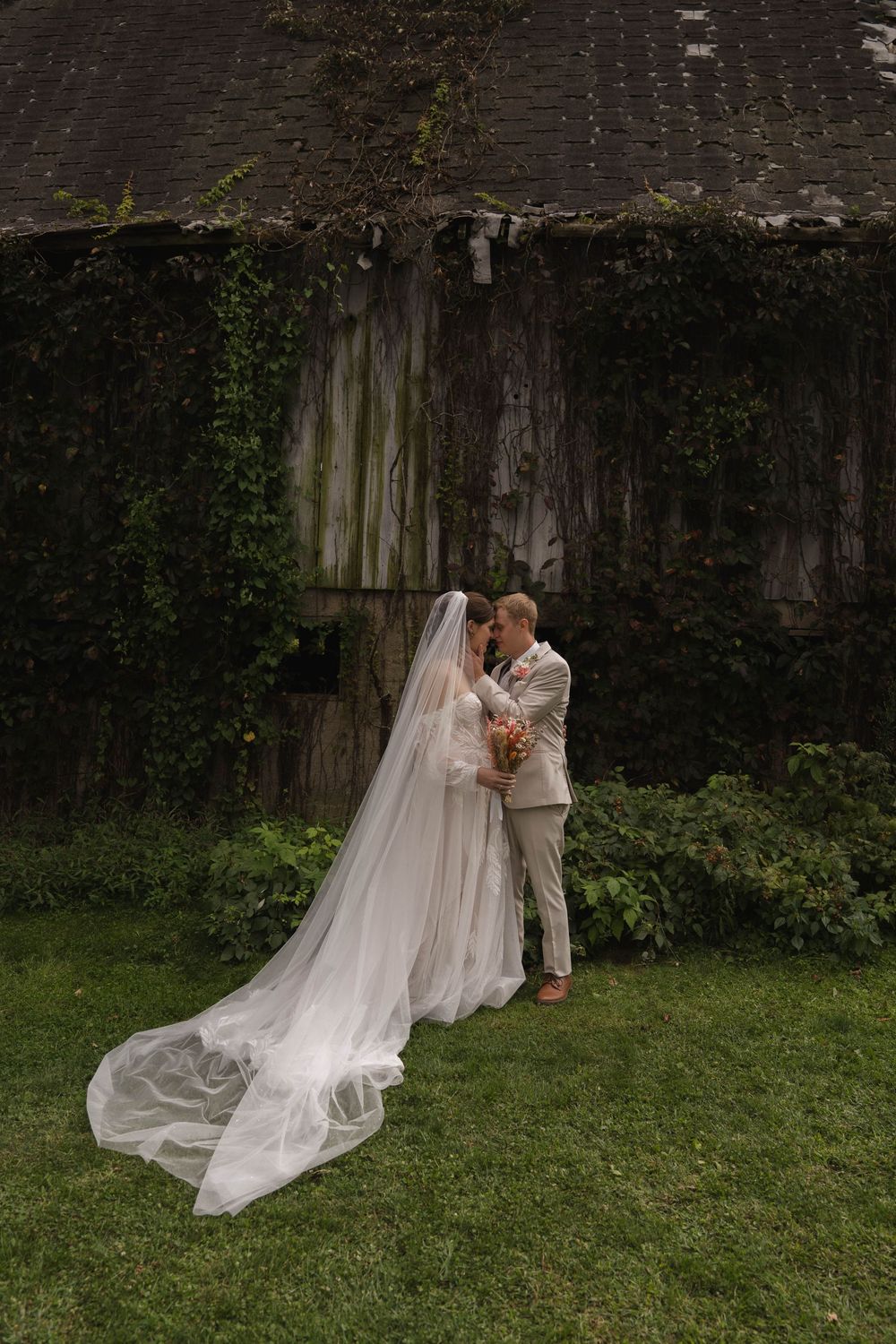 Elegant wedding scene with flowing veil against natural outdoor backdrop.