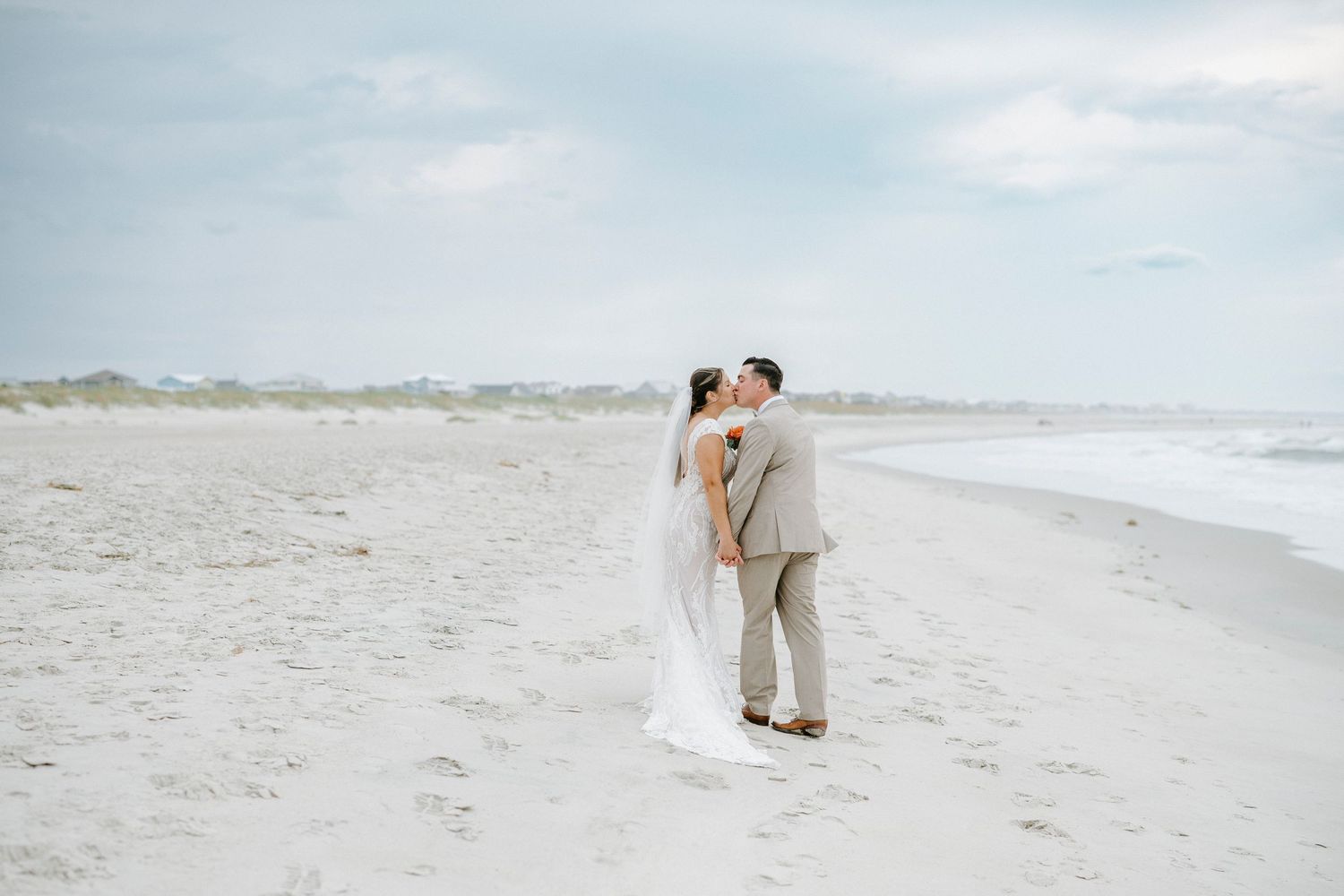 A peaceful beach wedding scene with couple walking along the shoreline as waves crash.