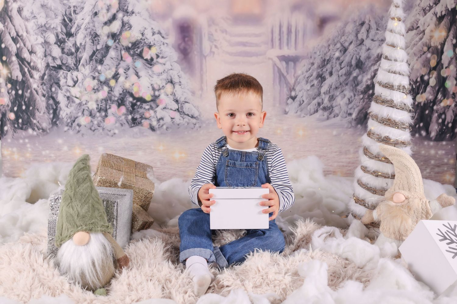 Holiday photo session setup with snowy winter wonderland backdrop, faux birch trees, and white decorative elements.