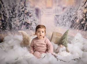 Winter wonderland photoshoot setup featuring snowy trees, white decor, and soft pink accents in a professional studio setting.