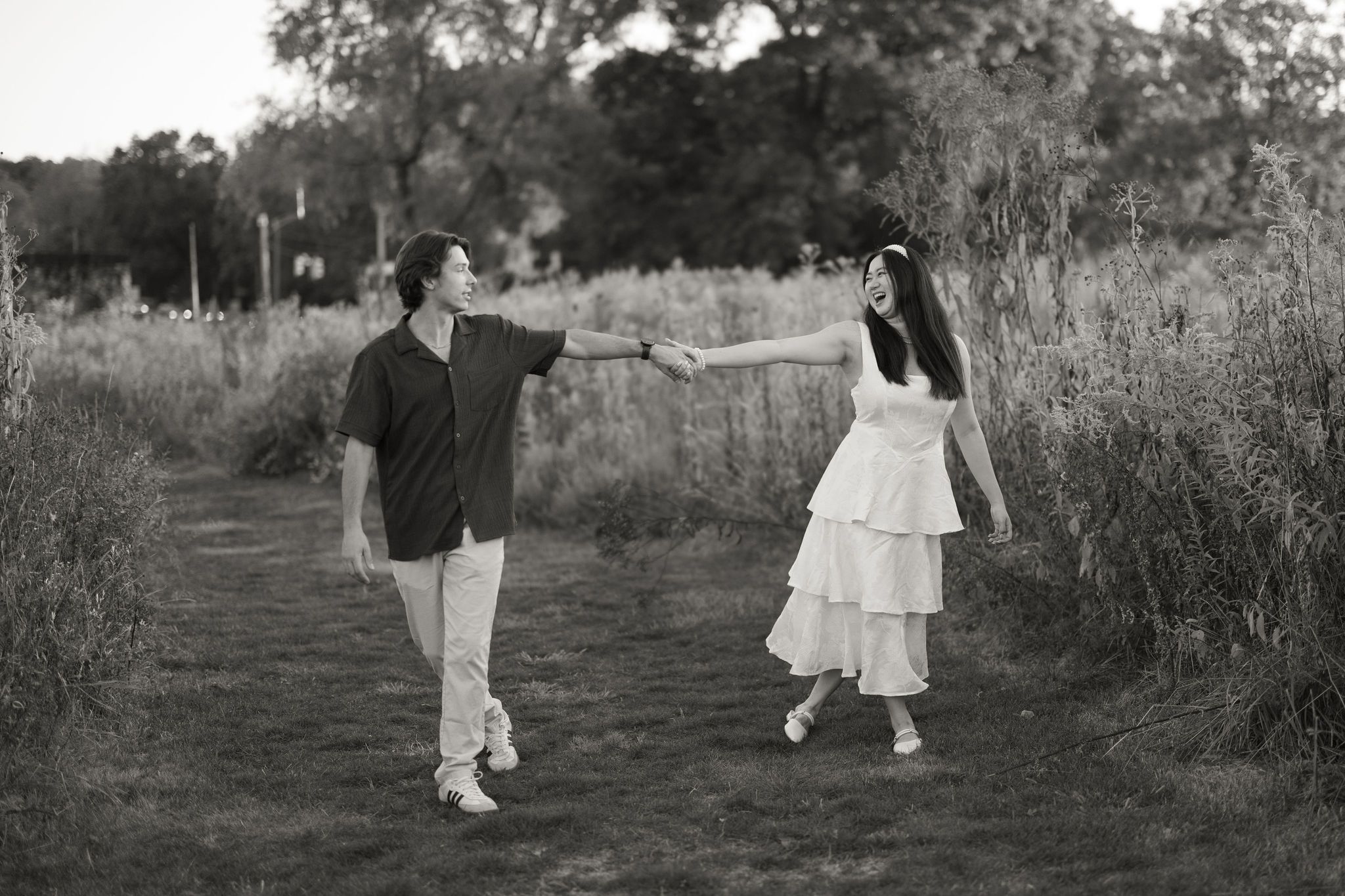 Vintage black and white photograph showing people in light-colored clothing walking together on a countryside path.