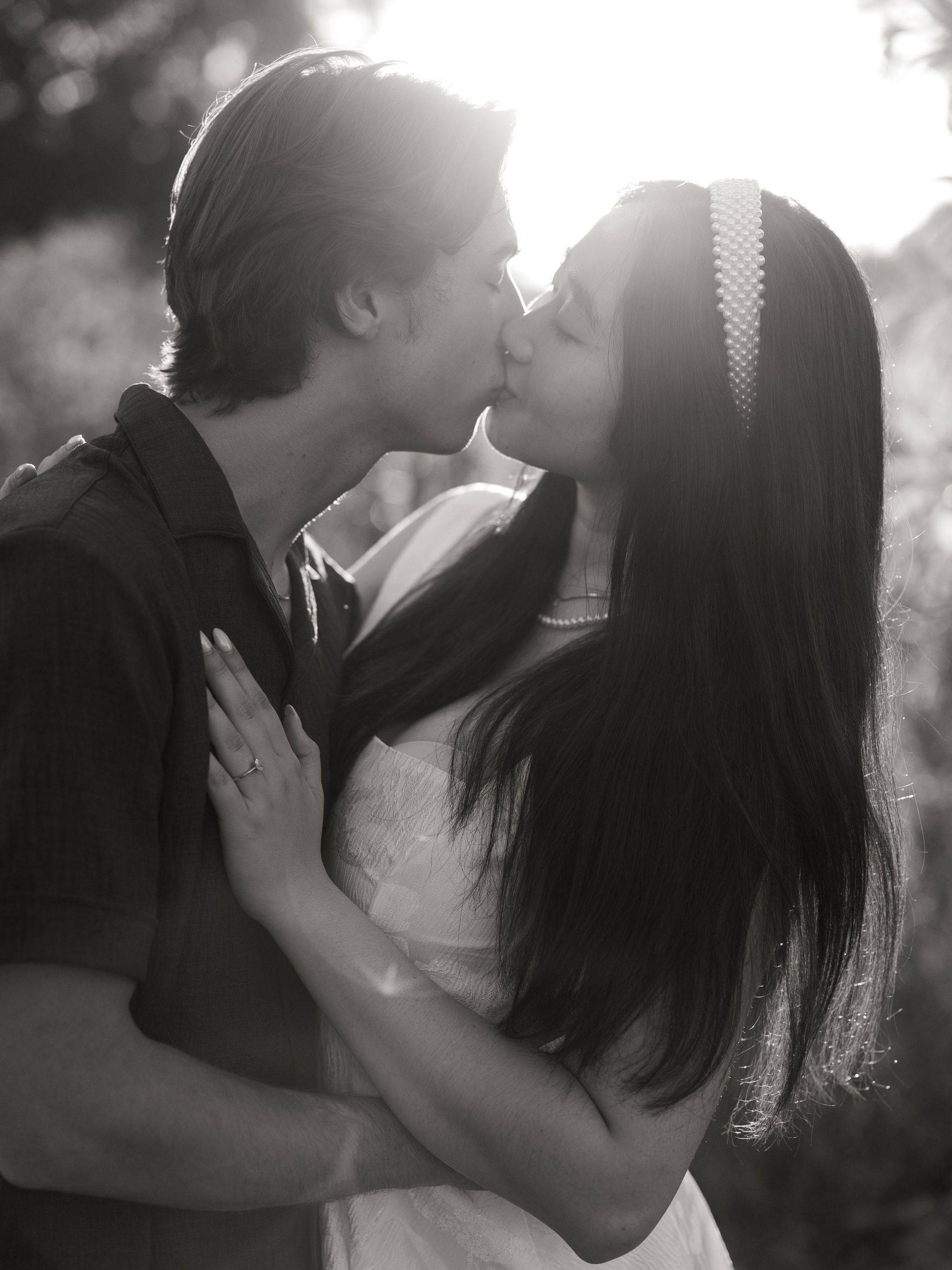 A romantic black and white photo sequence showing a couple sharing tender kisses in dreamy backlit lighting.