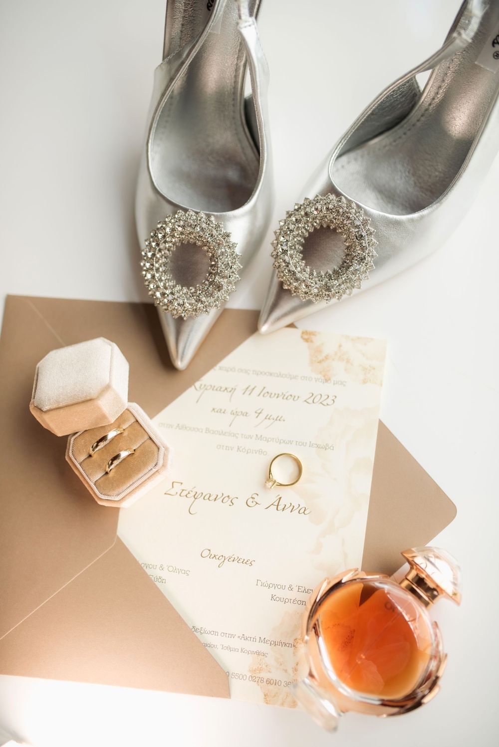 Elegant silver bridal shoes with crystal embellishments displayed with wedding invitation and jewelry box.