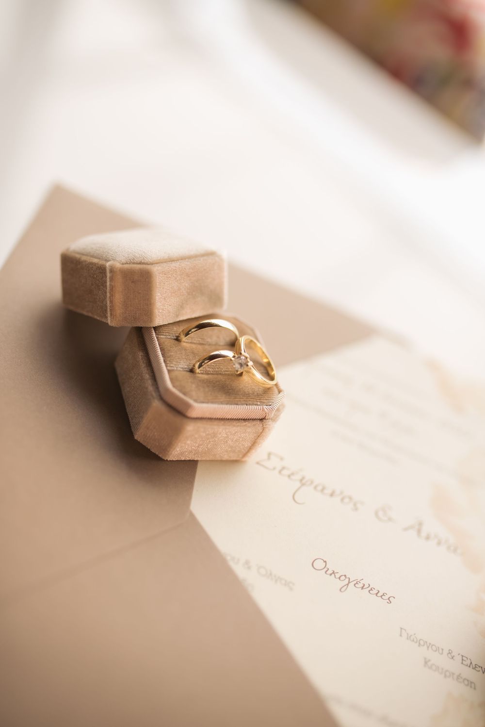Wedding rings nestled in small beige boxes with elegant calligraphy text.
