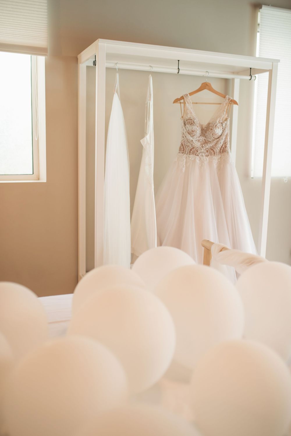 Ethereal wedding gowns displayed with white balloons creating a dreamy atmosphere.