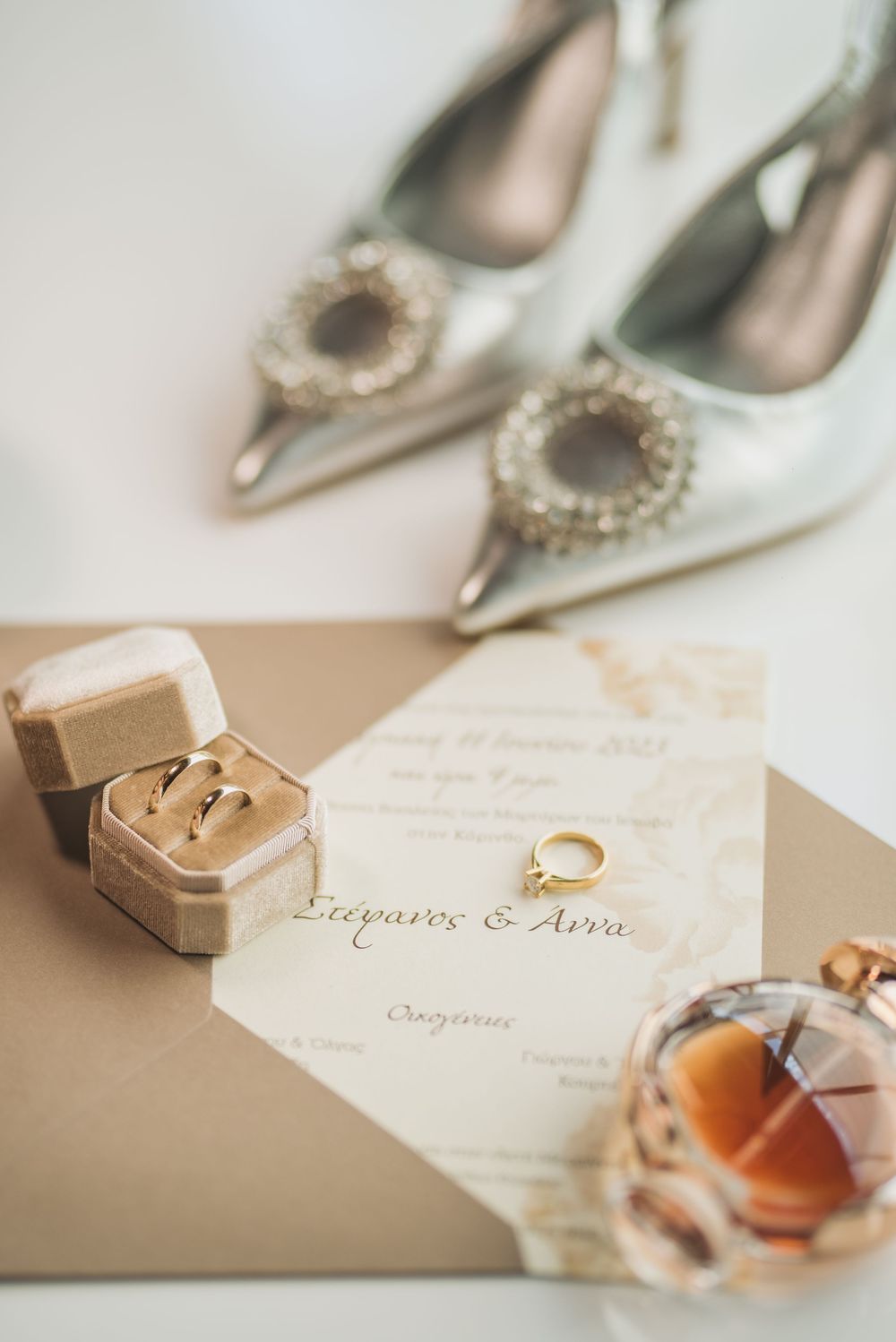 Wedding day details including silver shoes, rings, and invitations arranged on a light surface.