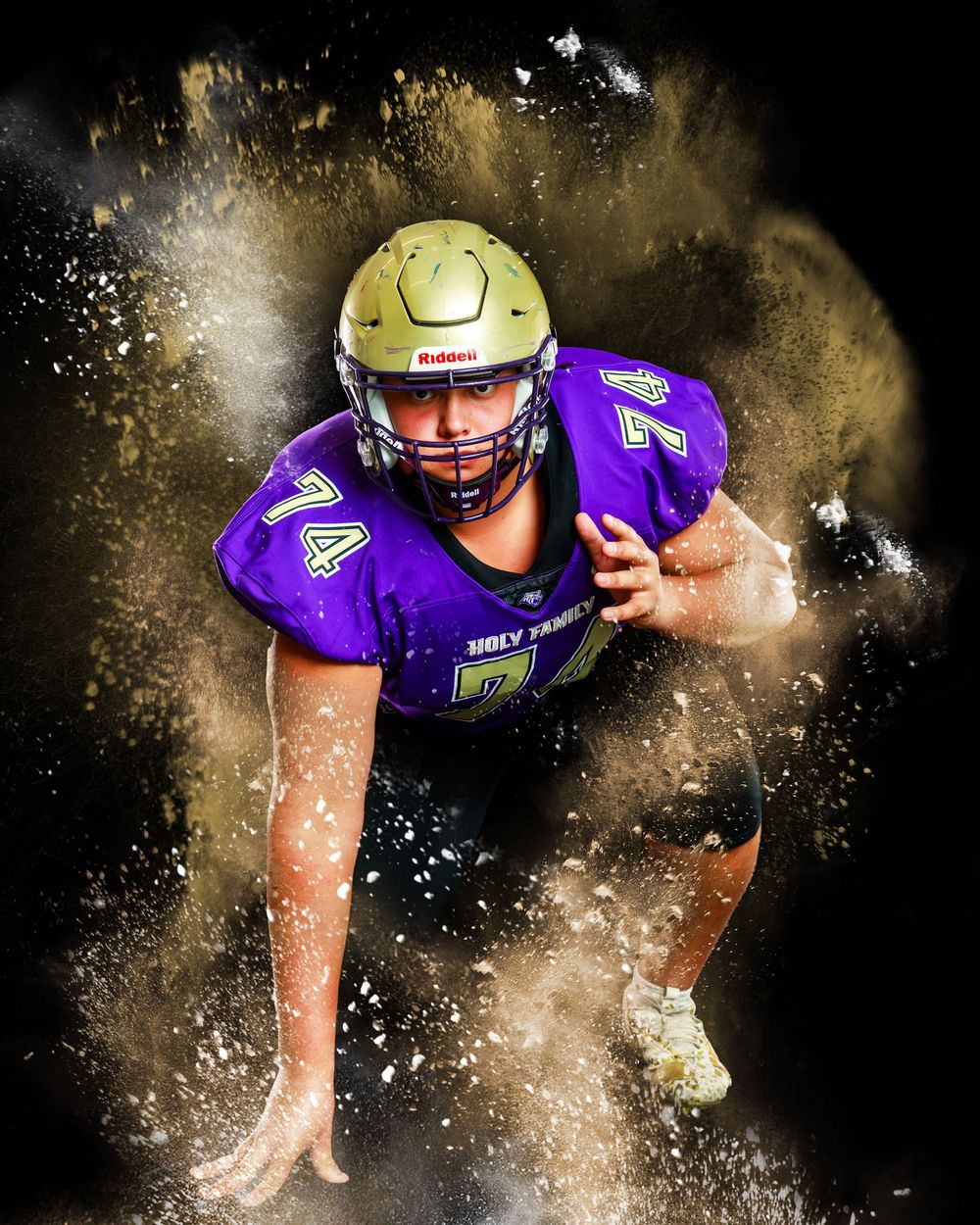 Action shot of football player bursting through gold dust effect on black background.