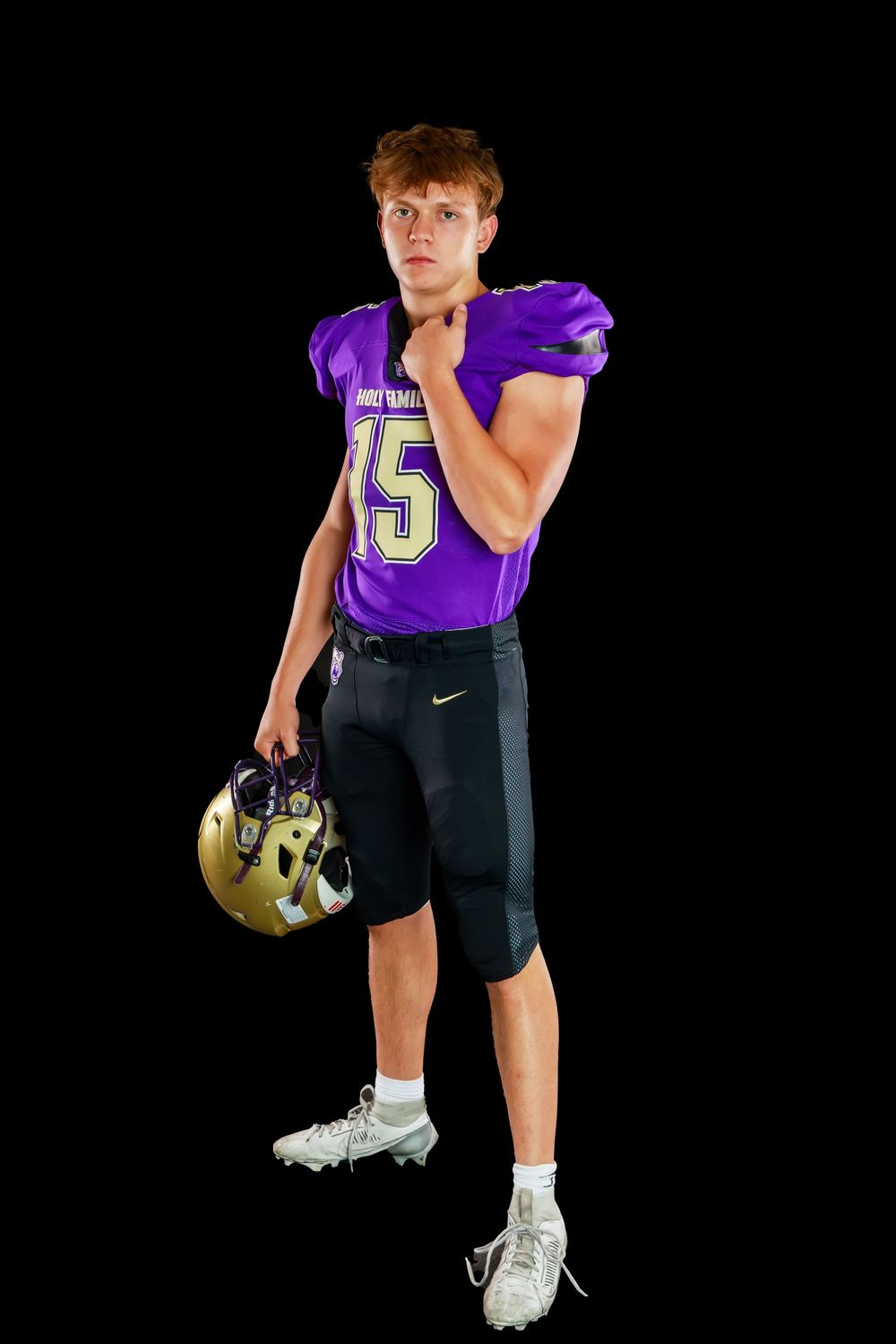 Football player in purple jersey and black shorts poses in athletic stance against dark background.