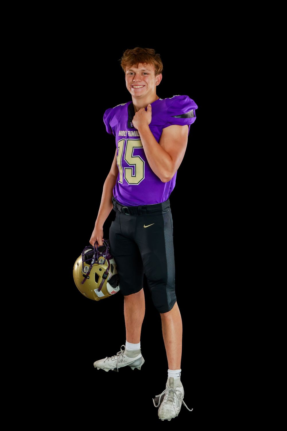 High school football player in purple and black Holy Family uniform performs dynamic side pose against dark background.